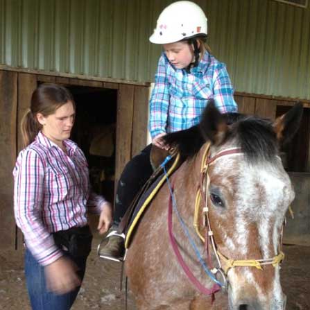 emma ward standing with a girl on a horse
